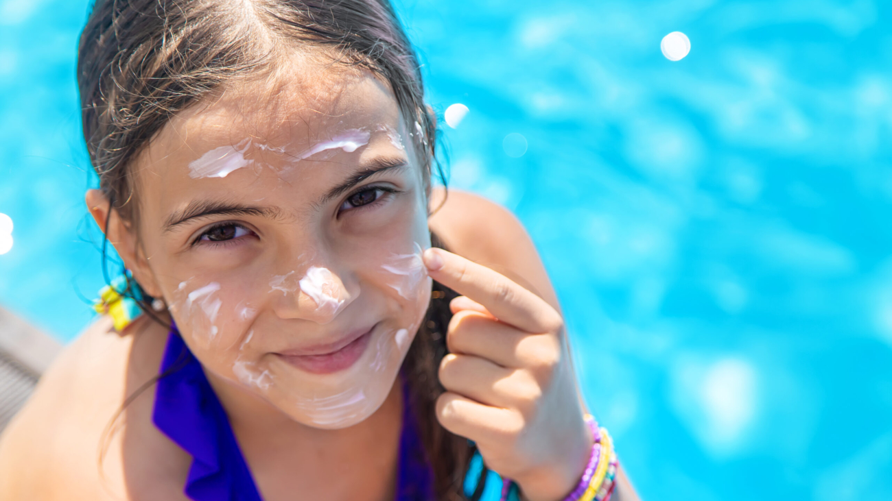 Child near the pool smears sunscreen. Selection focus. Kid.